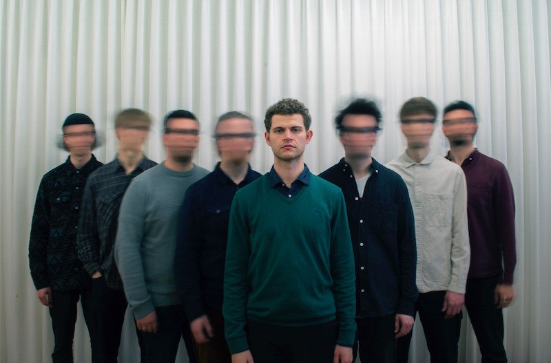 Ein Mann steht im Vordergrund, w&auml;hrend sieben M&auml;nner mit verschwommenen Gesichtern im Hintergrund stehen. Der Hintergrund ist ein wei&szlig;er Vorhang., &copy; Interessengemeinschaft Kultur Sindelfingen / B&ouml;blingen e.V.