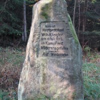 Gedenkstein im Wald erinnert an Forstpraktikant Wilh. Klingler, der 1913 im Kampf mit Wilderern fiel. Umgeben von Bäumen und Gras., © Natur.Nah. Schönbuch & Heckengäu