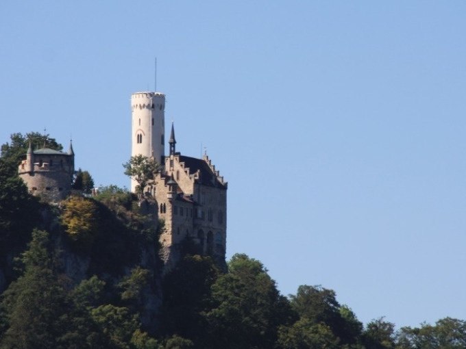 Burg Lichtenstein thront auf einem bewaldeten H&uuml;gel unter klarem, blauem Himmel., &copy; SwabianTravel
