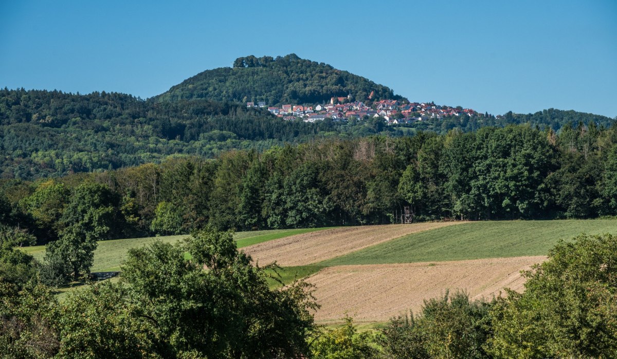 Ein Hügel mit einem Dorf auf der Spitze, umgeben von Wäldern und Feldern unter einem klaren blauen Himmel., © Landkreis Göppingen Ein Hügel mit einem Dorf auf der Spitze, umgeben von Wäldern und Feldern unter einem klaren blauen Himmel., © Landkreis Göppingen