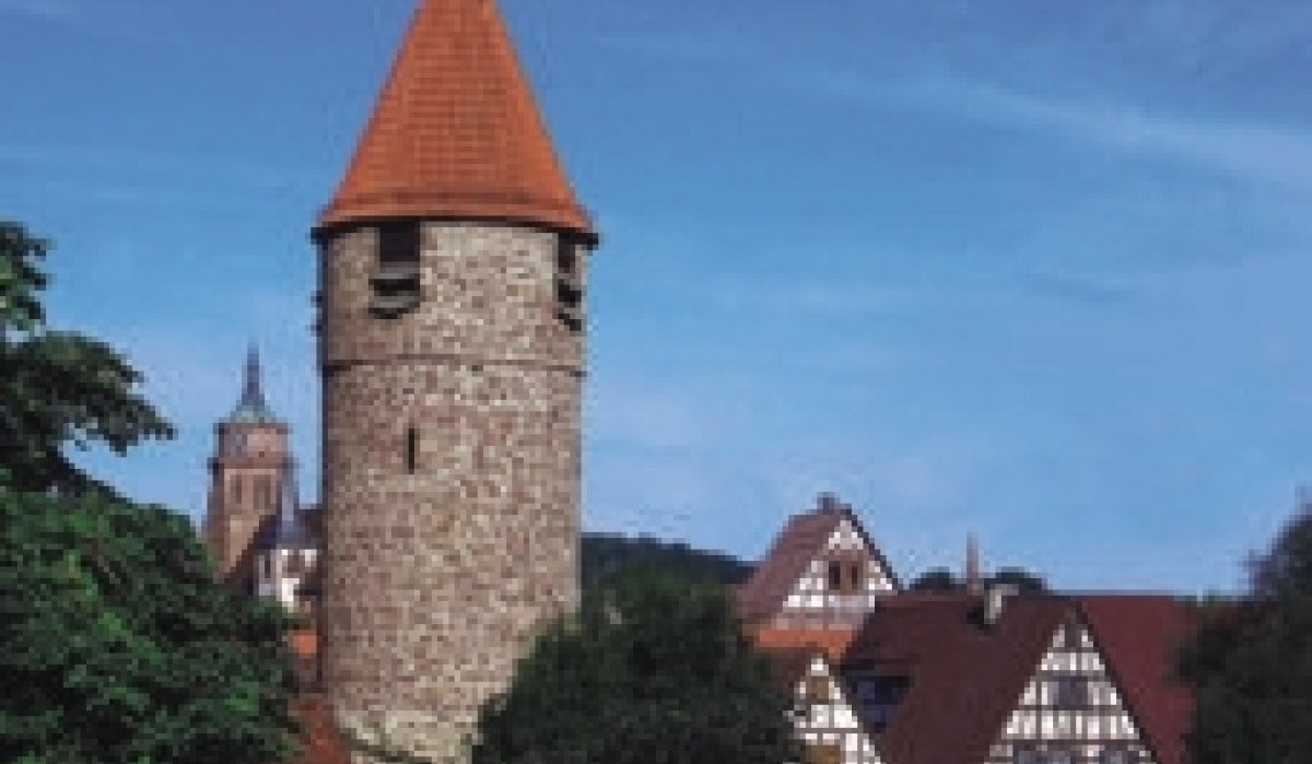 Ein runder Steinturm mit rotem Dach steht vor Fachwerkhäusern. Der Himmel ist blau und klar., © Sindelfingen - Stuttgart-Marketing GmbH