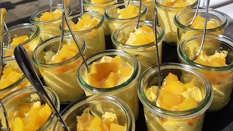 Mehrere kleine Gl&auml;ser mit gelbem Dessert, garniert mit Fruchtst&uuml;cken und L&ouml;ffeln, auf einem Tablett serviert., &copy; &copy; Servinho-Lohmann