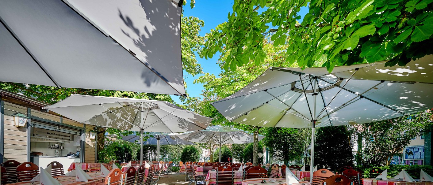 Gartenterrasse mit gedeckten Tischen unter großen Sonnenschirmen, umgeben von üppigem Grün und Bäumen., © Hotel Gasthof Hasen Gartenterrasse mit gedeckten Tischen unter großen Sonnenschirmen, umgeben von üppigem Grün und Bäumen., © Hotel Gasthof Hasen