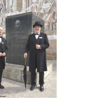 Zwei M&auml;nner in historischer Kleidung posieren vor einem Gottlieb-Daimler-Denkmal in Schorndorf. Sie tragen Anz&uuml;ge und H&uuml;te und halten Regenschirme., &copy; Eigenbetrieb Tourismus und Citymanagement Schorndorf
