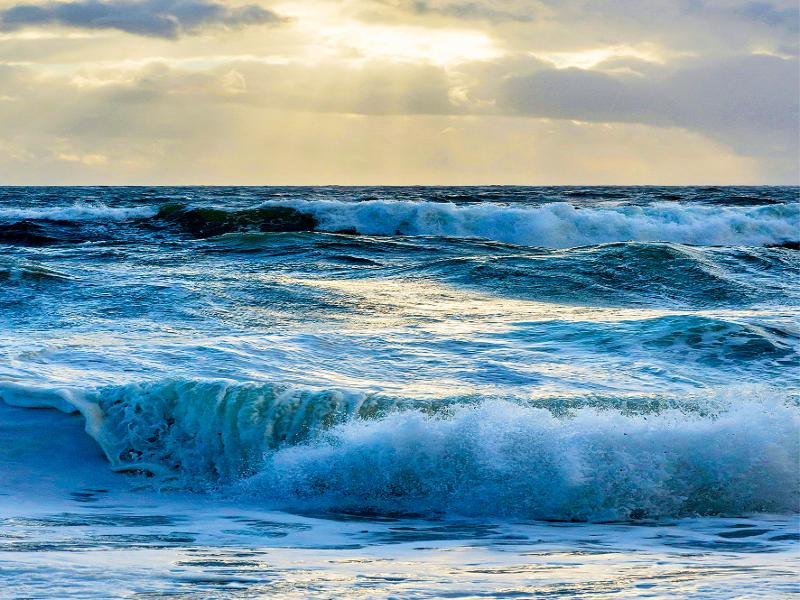 Dynamische Meereswellen unter einem bewölkten Himmel, durch den Sonnenstrahlen brechen. Die Szene vermittelt eine ruhige und zugleich kraftvolle Atmosphäre., © Backnang Dynamische Meereswellen unter einem bewölkten Himmel, durch den Sonnenstrahlen brechen. Die Szene vermittelt eine ruhige und zugleich kraftvolle Atmosphäre., © Backnang