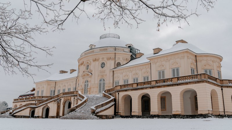 Schloss Solitude im Winter, bedeckt mit Schnee. Ein prächtiges Gebäude mit geschwungenen Treppen und kahlen Bäumen im Vordergrund., © SMG Thomas Niedermüller