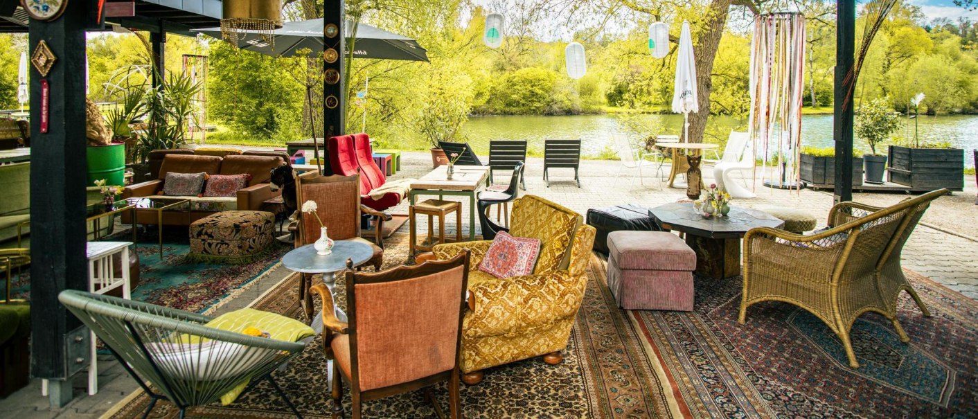 Gemütliche Outdoor-Lounge mit bunten Möbeln und Teppichen, umgeben von grüner Natur und einem See im Hintergrund., © Stuttgart-Marketing GmbH, Sarah Schmid