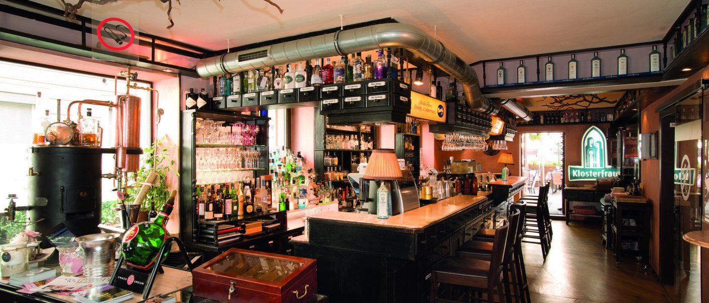 Bar mit Flaschen, Gläsern und Kupferdestille. Klosterfrau-Logo leuchtet im Hintergrund. Gemütliche Atmosphäre mit Holzmöbeln und Lampen., © Buschwerk Mediendesign-Wilhelmer Gastronomie Bar mit Flaschen, Gläsern und Kupferdestille. Klosterfrau-Logo leuchtet im Hintergrund. Gemütliche Atmosphäre mit Holzmöbeln und Lampen., © Buschwerk Mediendesign-Wilhelmer Gastronomie