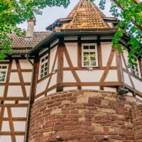 Fachwerkhaus mit roten Ziegeln und steinernem Sockel, umgeben von grünen Bäumen im Bohnenviertel., © SMG Thomas Niedermüller Fachwerkhaus mit roten Ziegeln und steinernem Sockel, umgeben von grünen Bäumen im Bohnenviertel., © SMG Thomas Niedermüller