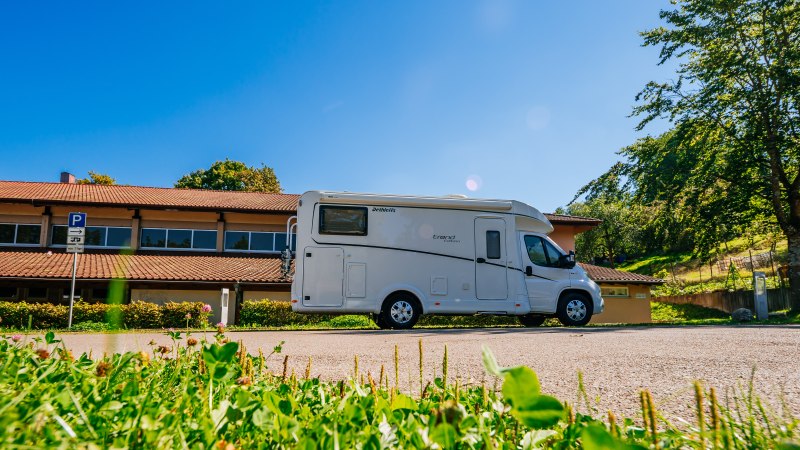 Wohnmobil auf einem Parkplatz vor einem Geb&auml;ude mit rotem Dach, umgeben von B&auml;umen und gr&uuml;nem Gras., &copy; Stuttgart-Marketing GmbH, Thomas Niederm&uuml;ller