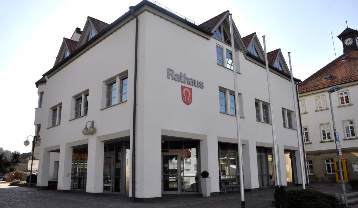 Das Nufringer Rathaus mit moderner Architektur, wei&szlig;en W&auml;nden und roten Dachziegeln. Vor dem Geb&auml;ude stehen Fahnenmasten., &copy; Natur.Nah. Sch&ouml;nbuch & Heckeng&auml;u