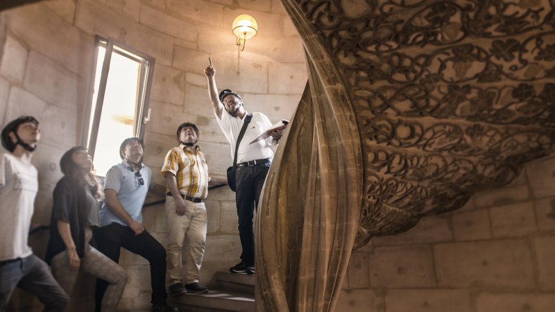 Gruppe von Menschen mit Helmen in einem historischen Gebäude, ein Mann zeigt nach oben. Verzierter Steinbogen im Hintergrund., © Stadtmarketing Göppingen