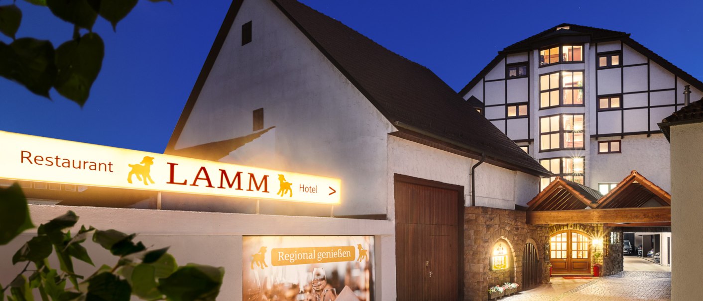 Eingang eines Hotels bei Nacht mit beleuchtetem Schild 'Restaurant Lamm'. Fachwerkhaus im Hintergrund, gepflasterter Weg führt zum Eingang., © Hotel Restaurant Lamm