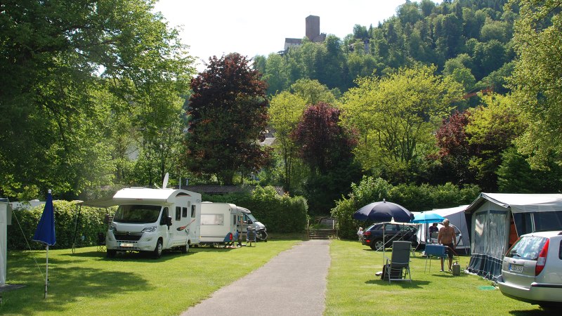 Campingplatz mit Wohnmobilen und Zelten, umgeben von grünen Bäumen und Hügeln. Im Hintergrund ist eine Burg auf einem Hügel zu sehen., © Campingpark Bad Liebenzell, Andreas Harter Campingplatz mit Wohnmobilen und Zelten, umgeben von grünen Bäumen und Hügeln. Im Hintergrund ist eine Burg auf einem Hügel zu sehen., © Campingpark Bad Liebenzell, Andreas Harter