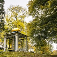 Ein Pavillon mit goldener Kuppel steht im Kurpark von Bad Wildbad, umgeben von herbstlich gefärbten Bäumen und einem grünen Rasen., © SMG, Sarah Schmid