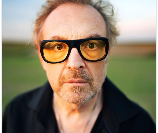 Ein Mann mit gelber Brille und ernstem Blick steht im Freien. Der Hintergrund ist unscharf, der Himmel zeigt einen sanften Farbverlauf., &copy; Konzertkreis Triangel Compagnia Compostelli e.V.