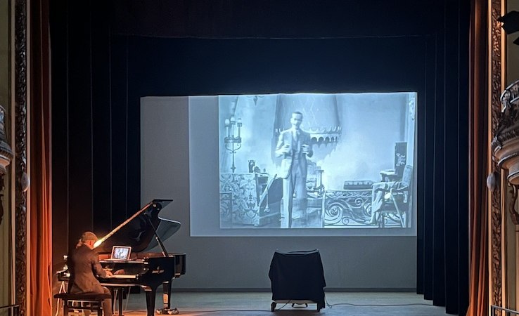 Ein Pianist begleitet live einen Stummfilm auf einer B&uuml;hne. Der Film wird auf eine Leinwand projiziert, w&auml;hrend das Publikum zuschaut., &copy; Touristik Bad Wildbad GmbH