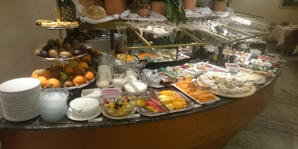 Ein Frühstücksbuffet mit einer Auswahl an Obst, Käse, Joghurt, Brot und Milch. Teller und Schalen sind bereitgestellt., © Hotel Unger