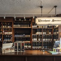 Theke im Weinhaus Stetter mit Regalen voller Weinflaschen und einem h&ouml;lzernen Tresen. Ein Schild mit der Aufschrift 'Weinhaus Stetter' h&auml;ngt von der Decke., &copy; Stuttgart Marketing GmbH, Sarah Schmid