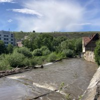 Ein Fluss flie&szlig;t durch Besigheim, ges&auml;umt von Geb&auml;uden und &uuml;ppiger Vegetation. Im Hintergrund sind Weinberge zu sehen., &copy; Stadt Besigheim