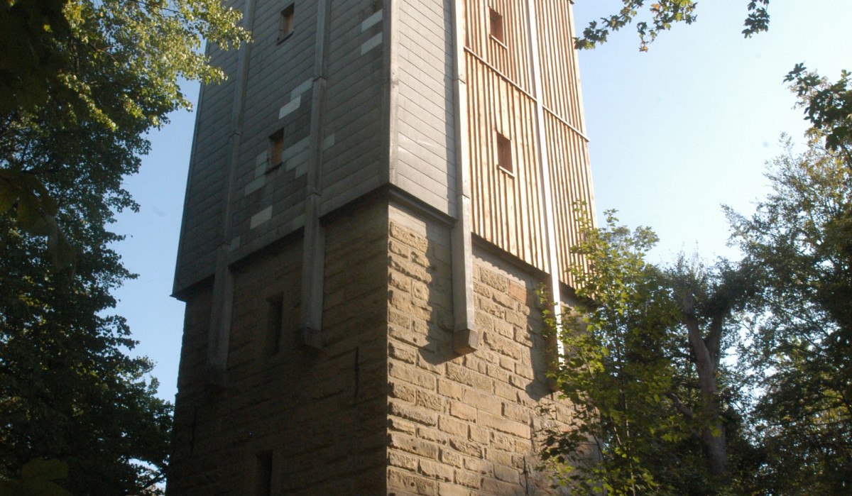 Ein hoher Turm aus Stein und Holz steht im Wald, umgeben von Bäumen. Der Himmel ist klar und sonnig., © TGMB Marbach Ein hoher Turm aus Stein und Holz steht im Wald, umgeben von Bäumen. Der Himmel ist klar und sonnig., © TGMB Marbach