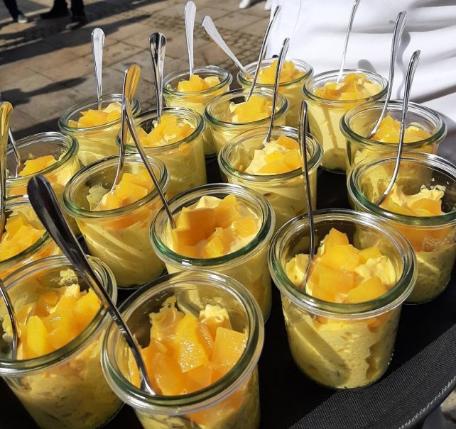 Mehrere kleine Gl&auml;ser mit gelbem Dessert, garniert mit Fruchtst&uuml;cken und L&ouml;ffeln, auf einem Tablett serviert., &copy; &copy; Servinho-Lohmann