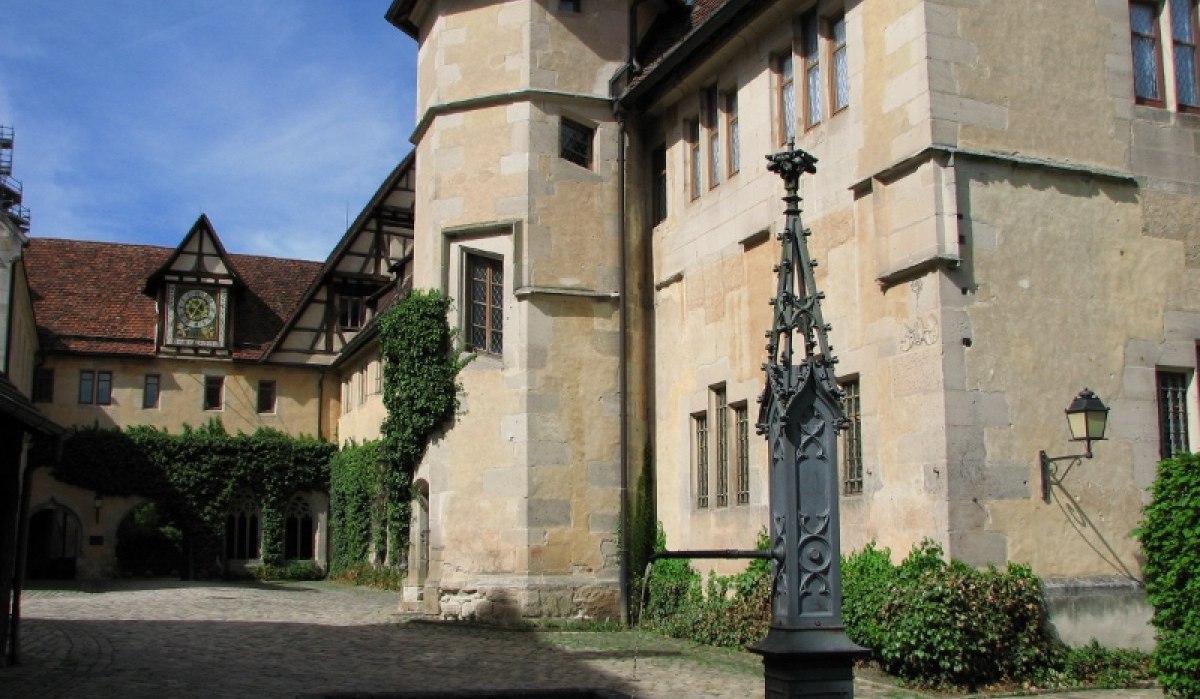 Historischer Innenhof mit Turm, Brunnen und bewachsenen Wänden. Ein Uhrturm ist im Hintergrund sichtbar, der Himmel ist blau., © Natur.Nah. Schönbuch & Heckengäu