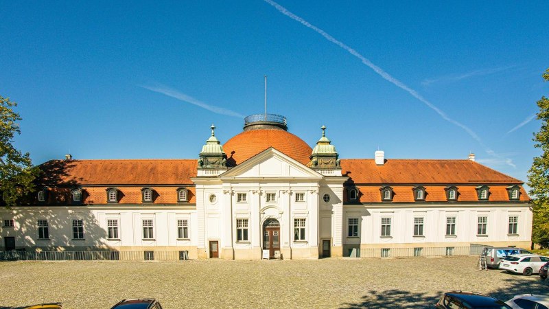 Das Schillermuseum in Marbach am Neckar zeigt seine beeindruckende Architektur mit rotem Dach und blauer Kuppel. Autos parken davor, umgeben von B&auml;umen., &copy; Stuttgart-Marketing GmbH, Sarah Schmid