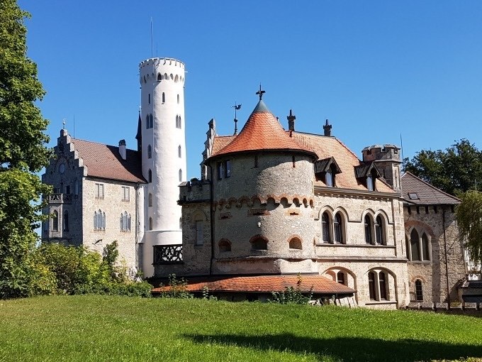 Schloss Lichtenstein mit seinen markanten T&uuml;rmen und roten D&auml;chern vor einem klaren blauen Himmel., &copy; SwabianTravel