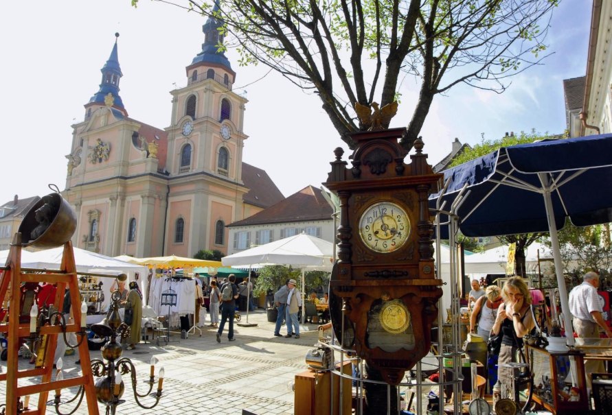 Antikmarkt in Ludwigsburg mit Ständen voller Antiquitäten. Im Hintergrund ist eine Kirche zu sehen. Besucher schlendern durch die Stände., © Tourismus & Events Ludwigsburg Antikmarkt in Ludwigsburg mit Ständen voller Antiquitäten. Im Hintergrund ist eine Kirche zu sehen. Besucher schlendern durch die Stände., © Tourismus & Events Ludwigsburg