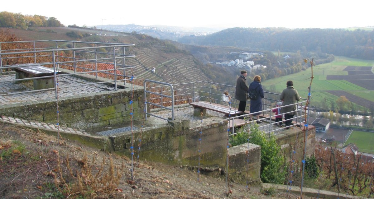 Menschen stehen auf einer Aussichtsplattform und blicken auf Weinberge und eine weite Landschaft. Herbstliche Farben dominieren die Szene., &copy; Land der 1000 H&uuml;gel - Kraichgau-Stromberg