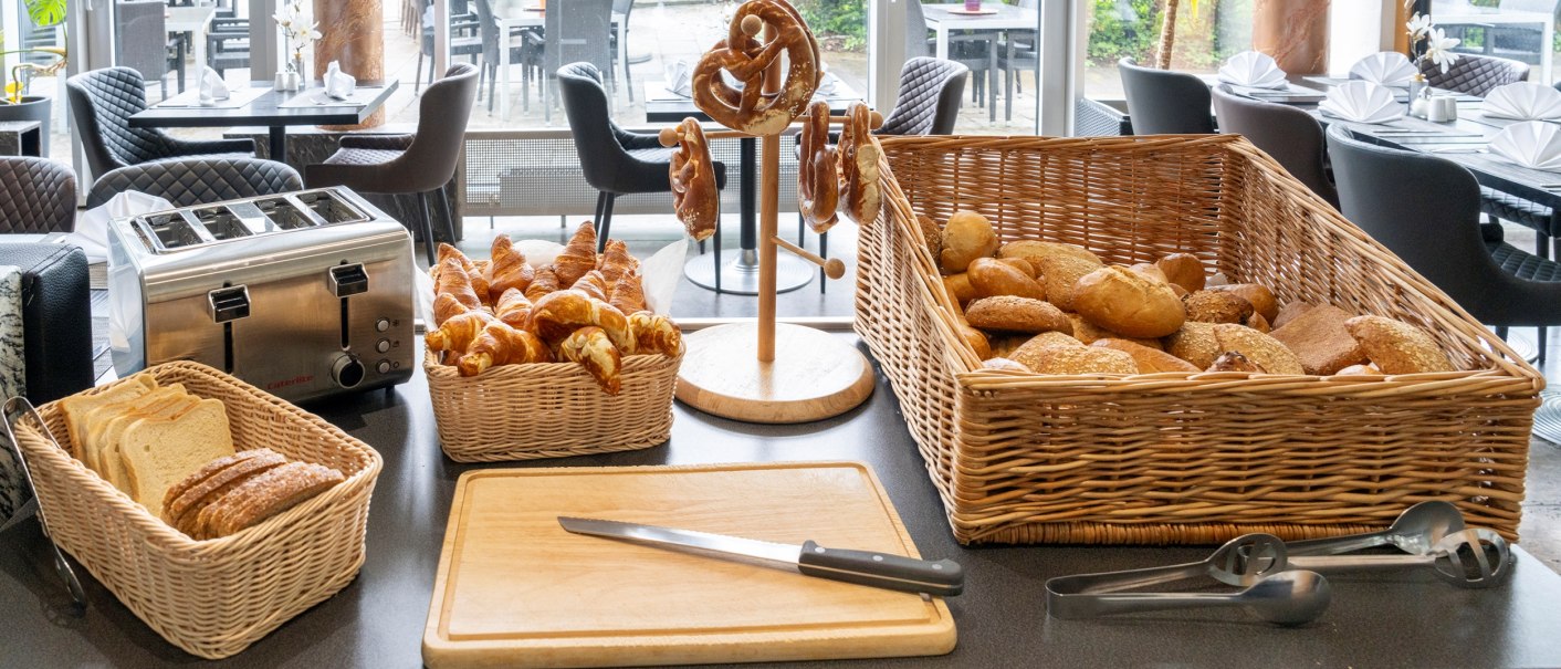Ein Frühstücksbuffet mit verschiedenen Brotsorten, Croissants, Brezeln und einem Toaster auf einem Tisch in einem Restaurant., © Plaza Residence Stuttgart-Ditzingen Ein Frühstücksbuffet mit verschiedenen Brotsorten, Croissants, Brezeln und einem Toaster auf einem Tisch in einem Restaurant., © Plaza Residence Stuttgart-Ditzingen