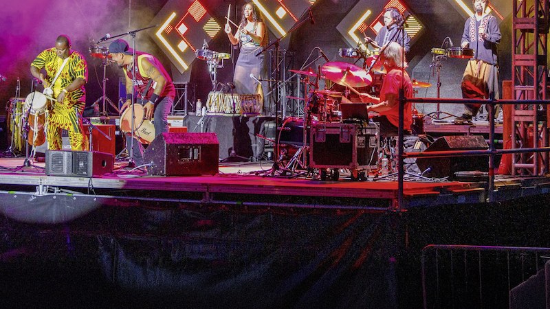 Eine Musikgruppe spielt auf einer B&uuml;hne, umgeben von bunten Lichtern und Rauch. Verschiedene Trommeln und Instrumente sind zu sehen., &copy; Stadtverwaltung Schorndorf