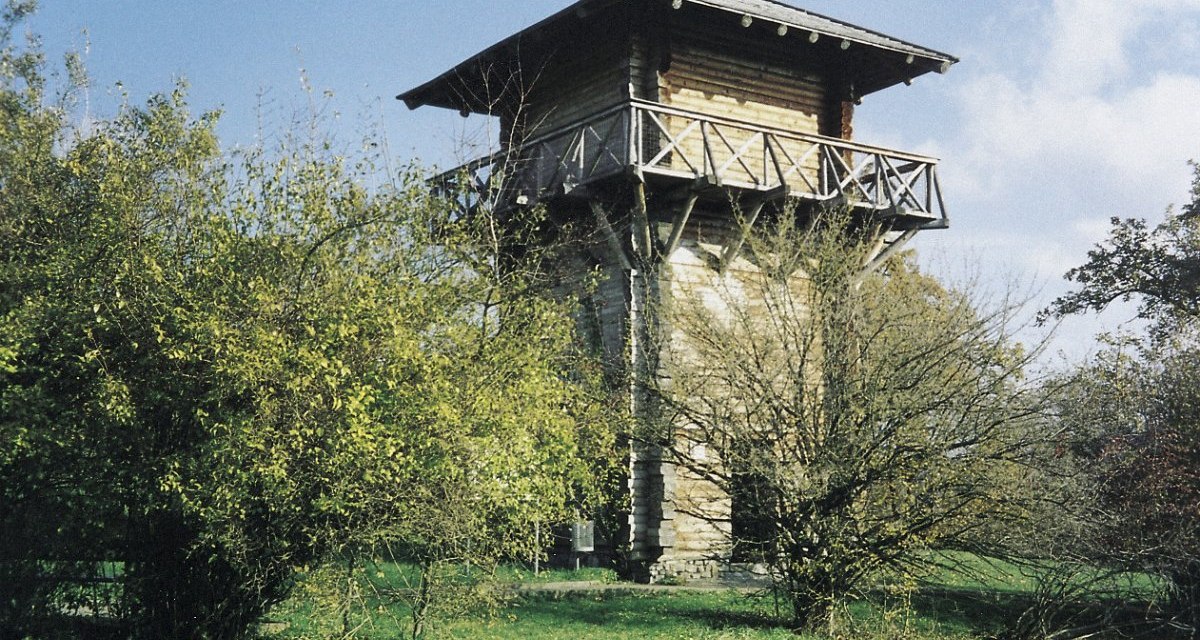 Rekonstruierter römischer Wachturm aus Holz mit umlaufendem Balkon, umgeben von Bäumen und Büschen auf einer grünen Wiese., © Remstal Tourismus e.V. Rekonstruierter römischer Wachturm aus Holz mit umlaufendem Balkon, umgeben von Bäumen und Büschen auf einer grünen Wiese., © Remstal Tourismus e.V.