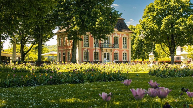 Ein elegantes, rosa Geb&auml;ude im Stadtpark von Schw&auml;bisch Gm&uuml;nd, umgeben von bl&uuml;henden Blumen und gr&uuml;nen B&auml;umen an einem sonnigen Tag., &copy; Stuttgart-Marketing GmbH, Sarah Schmid