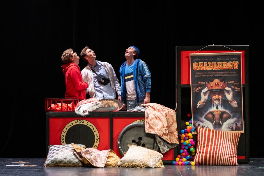 Drei Personen stehen vor einer Zauberb&uuml;hne, umgeben von Kissen und bunten B&auml;llen. Ein Plakat zeigt einen Zauberer mit einem Elefanten., &copy; G2 Baraniak