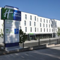 Das Holiday Inn Express in Sindelfingen zeigt eine moderne Fassade mit einem großen Parkplatzschild im Vordergrund. Der Himmel ist klar und blau., © tristar GmbH