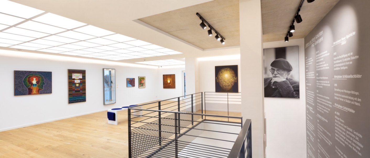 Modernes Kunsthaus mit Gemälden an weißen Wänden, Holzfußboden und einem Porträtfoto. Beleuchtung von oben, Treppengeländer im Vordergrund., © Freundeskreis Fritz Genkinger e.V. Modernes Kunsthaus mit Gemälden an weißen Wänden, Holzfußboden und einem Porträtfoto. Beleuchtung von oben, Treppengeländer im Vordergrund., © Freundeskreis Fritz Genkinger e.V.