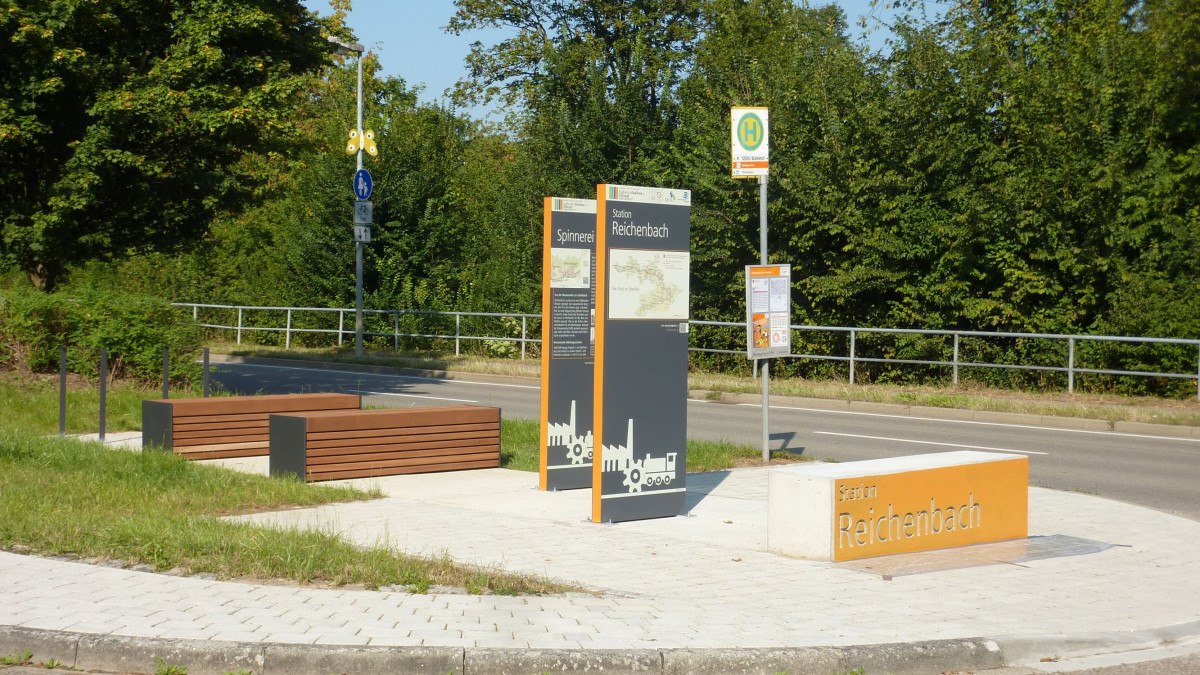 Station Reichenbach mit Infotafeln zur Industriekultur und Sitzbänken. Im Hintergrund eine Bushaltestelle und grüne Vegetation., © Verband Region Stuttgart