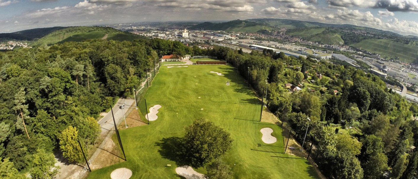 Luftaufnahme eines Golfplatzes in Stuttgart, umgeben von Bäumen und Hügeln, mit der Stadt im Hintergrund unter einem bewölkten Himmel., © GolfKultur Stuttgart Luftaufnahme eines Golfplatzes in Stuttgart, umgeben von Bäumen und Hügeln, mit der Stadt im Hintergrund unter einem bewölkten Himmel., © GolfKultur Stuttgart