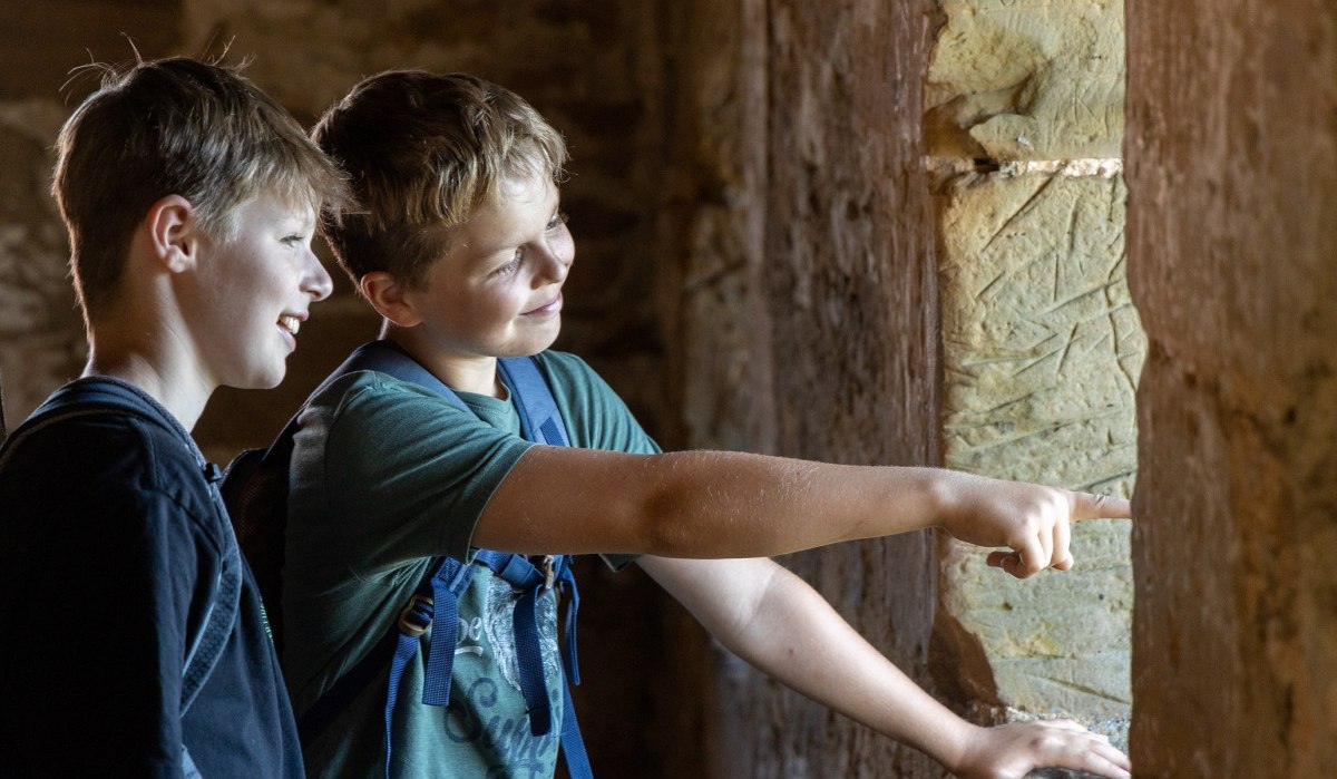 Zwei Jungen stehen in einer Burgruine und schauen lächelnd aus einem Fenster. Einer zeigt nach draußen., © Foto Thomas Zehnder Zwei Jungen stehen in einer Burgruine und schauen lächelnd aus einem Fenster. Einer zeigt nach draußen., © Foto Thomas Zehnder