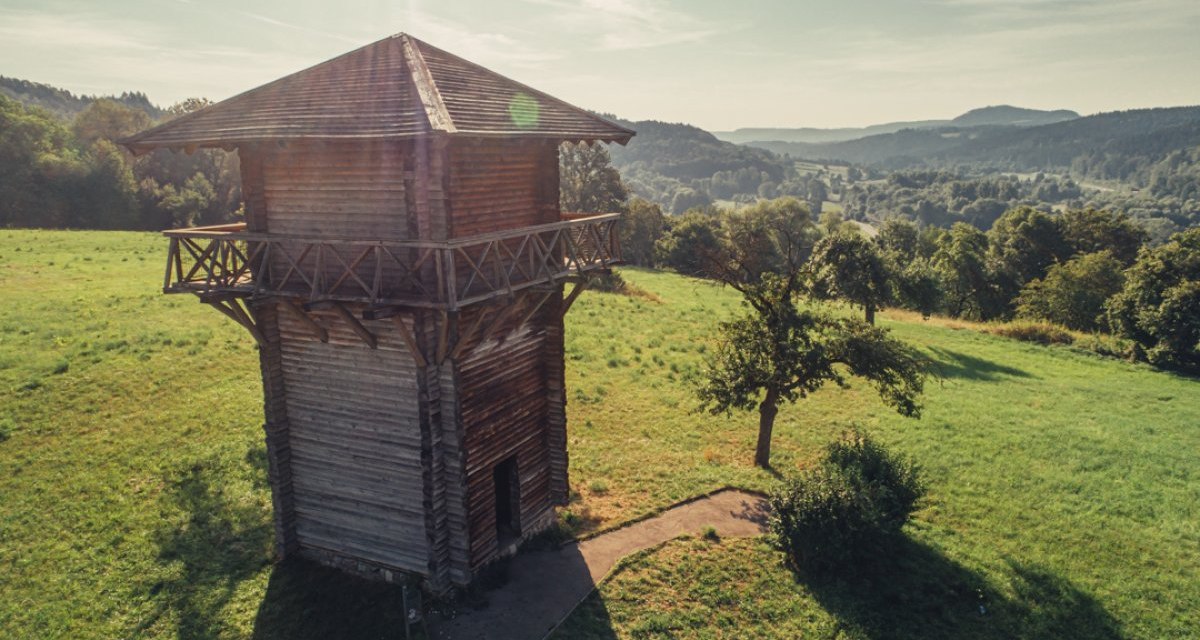 Holzwachturm auf grüner Wiese, umgeben von Bäumen und Hügeln im Hintergrund. Sonnenschein und klare Sicht., © Tourismus Ostalb Holzwachturm auf grüner Wiese, umgeben von Bäumen und Hügeln im Hintergrund. Sonnenschein und klare Sicht., © Tourismus Ostalb