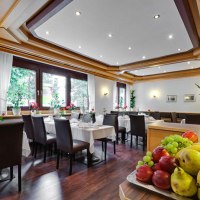 Eleganter Fr&uuml;hst&uuml;cksraum mit gedeckten Tischen, dunklen St&uuml;hlen und einer Obstschale im Vordergrund. Gro&szlig;e Fenster lassen viel Licht herein., &copy; ARNOTEL GmbH