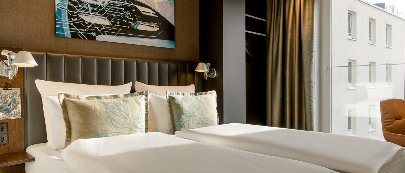 Modernes Hotelzimmer mit Doppelbett, Kunstwerk an der Wand, großen Fenstern und eleganter Einrichtung., © TOMAS