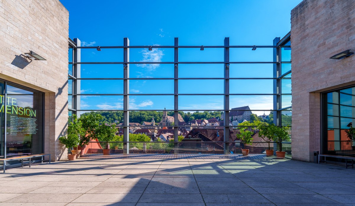 Terrasse der Kunsthalle Würth mit Glasfassade, Topfpflanzen und Blick auf die Altstadt von Schwäbisch Hall unter blauem Himmel., © Michael Kuehneisen Terrasse der Kunsthalle Würth mit Glasfassade, Topfpflanzen und Blick auf die Altstadt von Schwäbisch Hall unter blauem Himmel., © Michael Kuehneisen