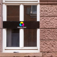 Zwei Fenster mit Schildern der Galerie Pixxl an einer roten Backsteinwand. Die Schilder zeigen ein buntes Logo und den Namen der Galerie., &copy; Stuttgart-Marketing GmbH, Sarah Schmid