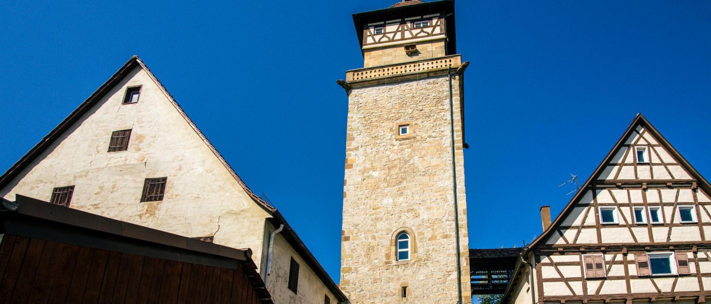 Der Hochwachturm in Waiblingen steht zwischen zwei Fachwerkhäusern unter klarem, blauem Himmel., © Stuttgart-Marketing GmbH, Sarah Schmid