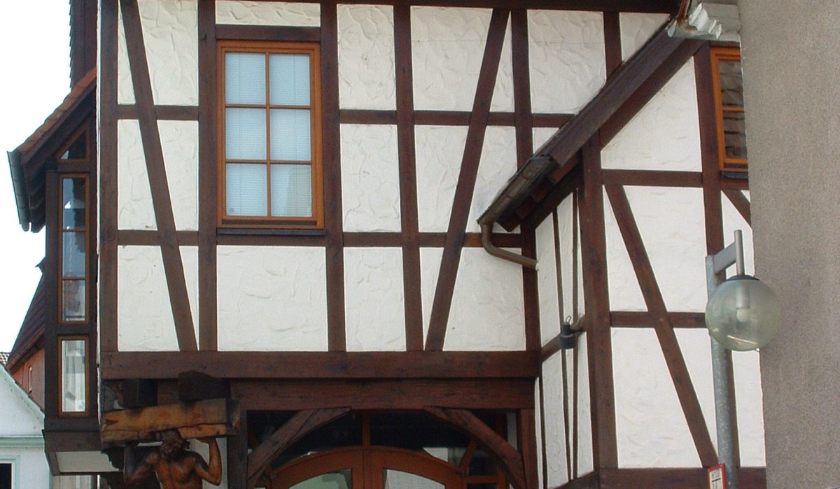 Fachwerkhaus mit markanter Holztür und geschnitzter Figur an der Fassade. Traditionelle Architektur in Künzelsau, Deutschland., © Touristikgemeinschaft Hohenlohe e. V. | Marion Schlund
