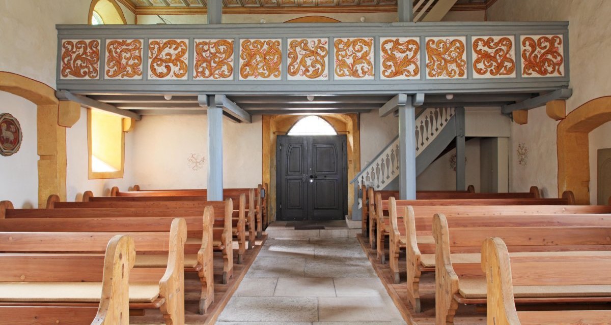 Innenansicht der Nikolauskirche in Waiblingen-Hegnach. Holzbänke, bemalte Decke und eine Empore mit verzierten Paneelen sind sichtbar., © Waiblingen - Stuttgart-Marketing GmbH Innenansicht der Nikolauskirche in Waiblingen-Hegnach. Holzbänke, bemalte Decke und eine Empore mit verzierten Paneelen sind sichtbar., © Waiblingen - Stuttgart-Marketing GmbH