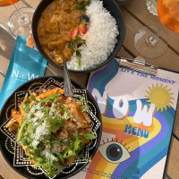 Ein Tisch mit Curry und Reis, Pasta mit Rucola, einem Getr&auml;nk und einer bunten Speisekarte mit der Aufschrift 'NOW'., &copy; cNOW